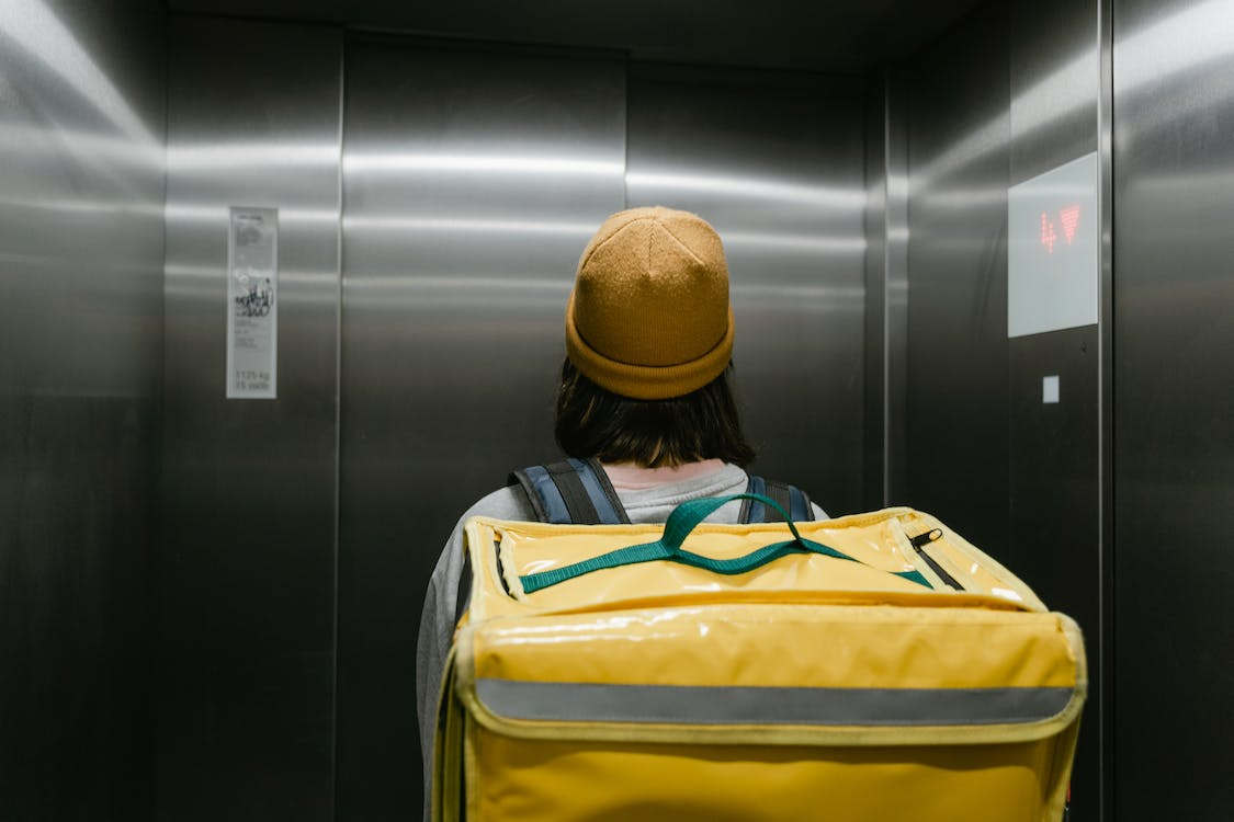 A person inside an elevator with yellow bag